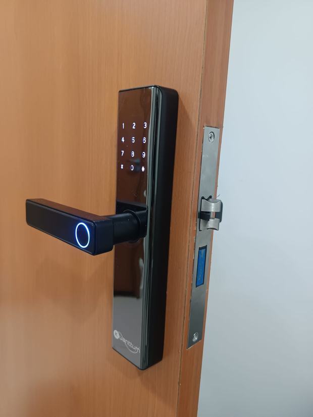 Fechadura digital preta com maçaneta e leitor biométrico em porta de madeira clara