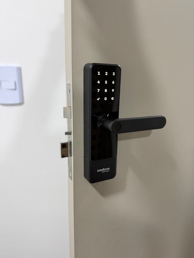 Fechadura digital preta com teclado touch em porta branca